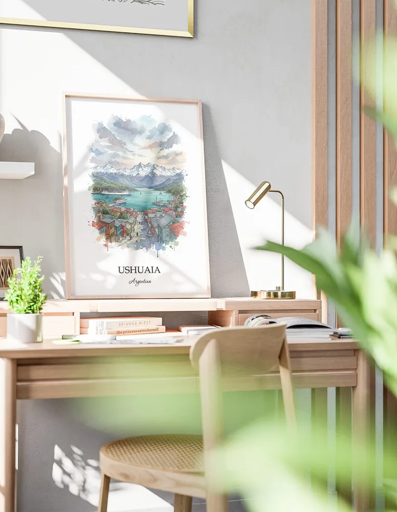 Cozy, well-lit workspace with a minimalist poster of Ushuaia, Argentina in a light frame sitting on the desk.