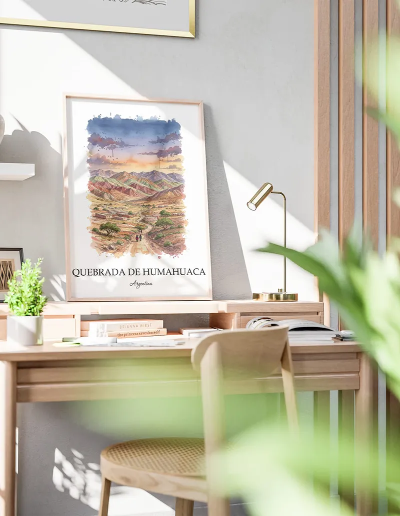 Cozy, well-lit workspace with a minimalist poster of Quebrada de Humahuaca, Argentina in a light frame sitting on the desk.